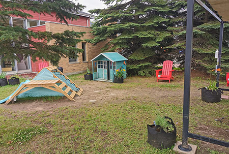 La place éphémère La Rassembleuse dispose d'un mobilier de jeux pour les enfants, incluant une maisonnette et un module d'habilité